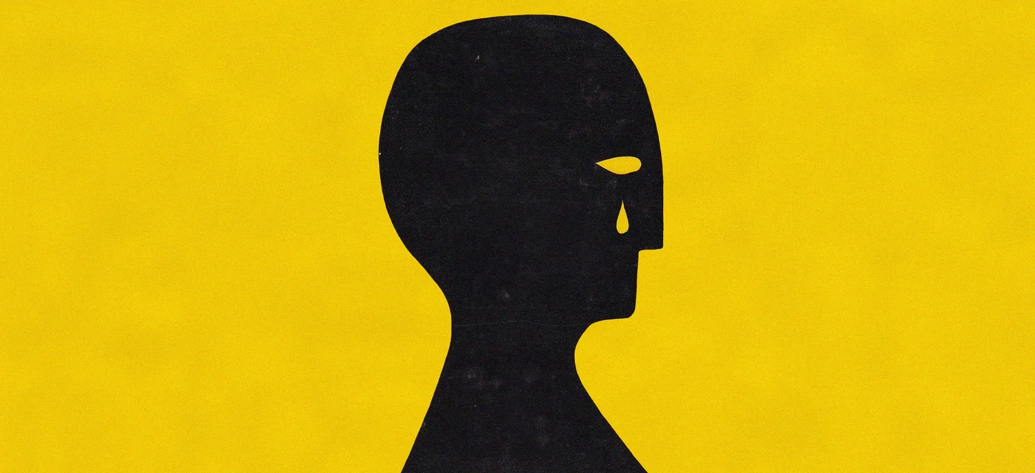 Black silhouette of a person's profile with a teardrop near the eye, set against a yellow background.